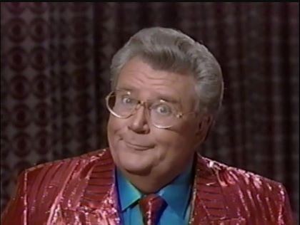 Rod is wearing a shiny red/red-striped jacket with matching necktie & aqua silk shirt