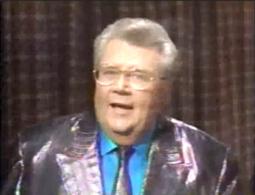 Rod is wearing a shiny purple jacket, matching necktie & light-blue collarless silk shirt