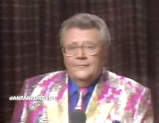 Rod is wearing a shiny pink and silver jacket with gold lapels, matching necktie & a blue shirt with matching pocket square