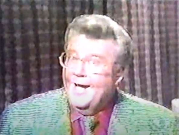 Rod is wearing a green sequined jacket, matching tie & red shirt