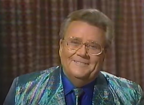 Rod is wearing a holographic-green jacket with matching tie & blue shirt