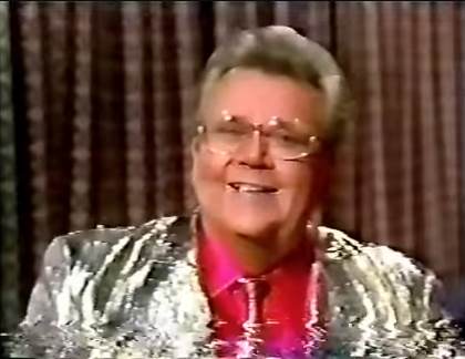 Rod is wearing a gold jacket with matching necktie & a red shirt