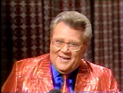 Rod is wearing a shiny red/red-striped jacket, matching tie & blue silk shirt