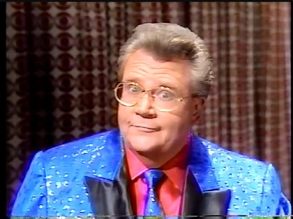 Rod is wearing a blue jacket with silver spots & black lapels, matching necktie & red silk shirt