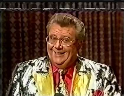 Rod is wearing a black and silver jacket with gold lapels, matching necktie & a pink silk shirt with matching pocket square