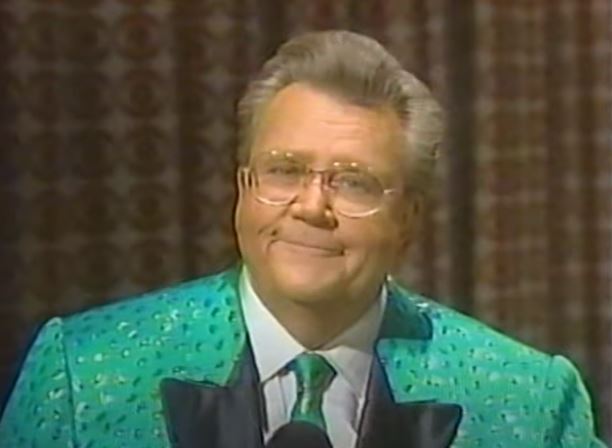 Rod is wearing a green/mottled shiny green jacket & tie with black lapels & white shirt