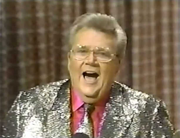 Rod is wearing a silver sequined jacket & tie with a red shirt