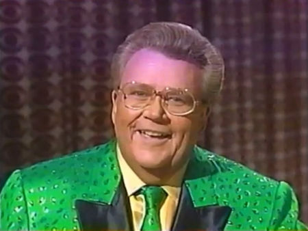 Rod is wearing a green jacket with silver spots, black lapels, a matching necktie & yellow silk shirt