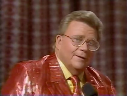 Rod is wearing a shiny red/red-striped jacket, matching necktie & yellow shirt