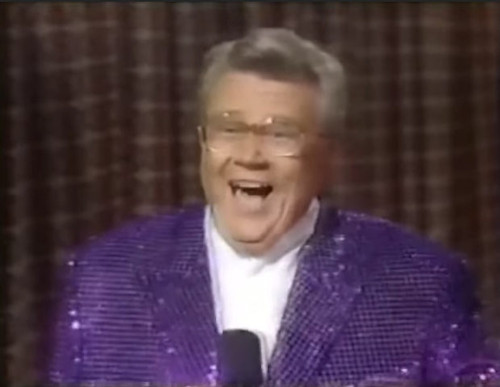 Rod is wearing a purple sequined jacket & white collarless silk shirt