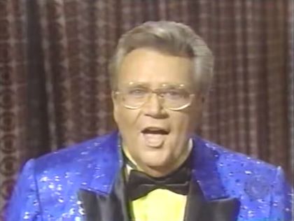 Rod is wearing a blue jacket with black lapels, a black bow tie & yellow collarless silk shirt