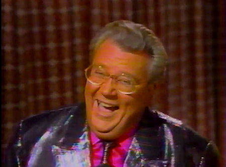 Rod is wearing a shiny purple/fuschia/blue striped jack w/ matching tie & a fuchsia silk shirt