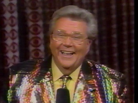 Rod is wearing a rainbow multi-colored sequined jacket with matching necktie & yellow shirt