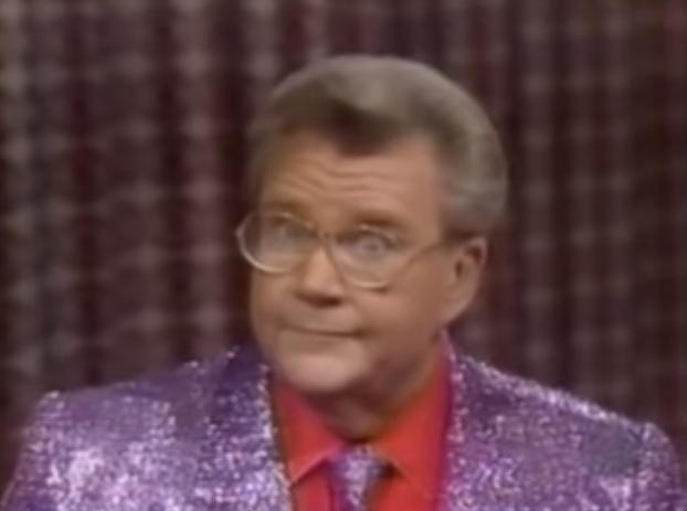 Rod is wearing a purple sequined jacket & tie with a red shirt
