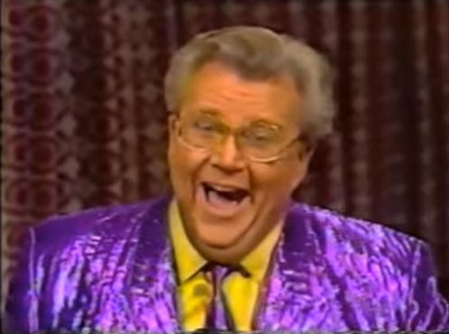 Rod is wearing a shiny purple/purple-striped jacket with matching tie & yellow shirt