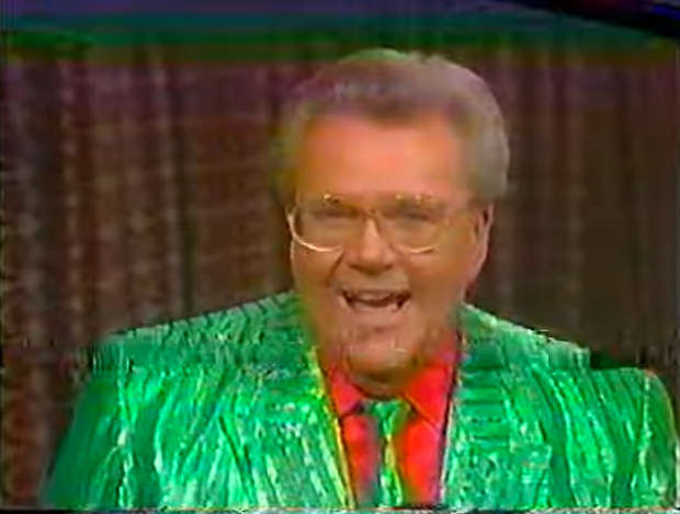 Rod is wearing a shiny green/green-striped jacket with matching necktie & a red shirt
