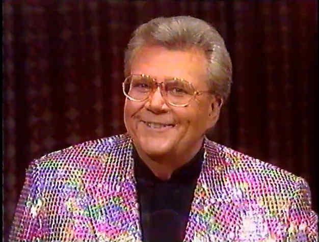 Rod is wearing a multi-colored sequined jacket & black collarless silk shirt