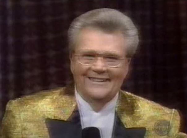 Rod is wearing a shiny gold jacket with black lapels & a white silk collarless shirt