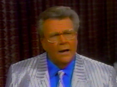 Rod is wearing a shiny silver jacket with grey pinstripes, matching necktie & blue silk shirt