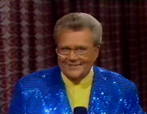 Rod is wearing a blue sequined jacket & yellow collarless silk shirt