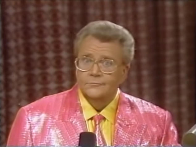 Rod is wearing a shiny pink jacket, matching necktie & yellow silk shirt