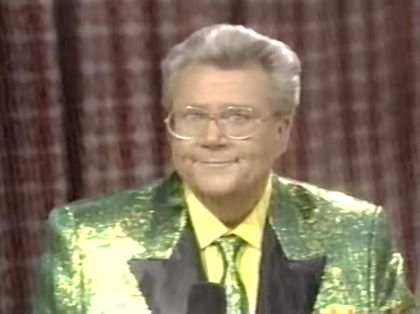 Rod is wearing a yellow-green sequined jacket with black lapels, matching necktie & yellow shirt