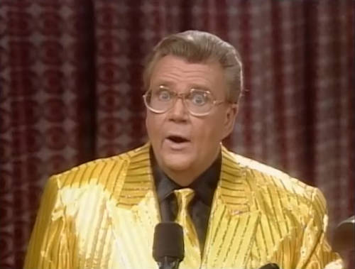 Rod is wearing a shiny yellow/yellow-striped jacket, matching necktie & a black silk shirt with matching pocket square