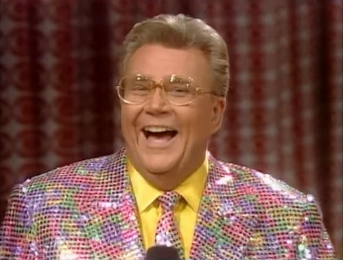 Rod is wearing a multi-colored sequined jacket, matching necktie & yellow silk shirt