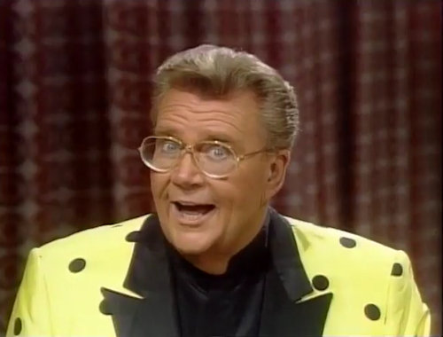 Rod is wearing a yellow jacket with black polka dots, black lapels & black collarless silk shirt
