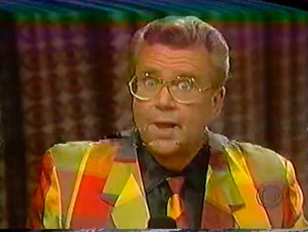 Rod is wearing a green/red/yellow/orange/purple jacket with matching tie & black shirt