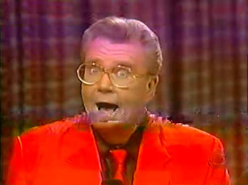 Rod is wearing a red jacket, matching neck tie & black shirt