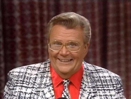 Rod is wearing a black & white checked hounds tooth jacket, matching tie & red shirt