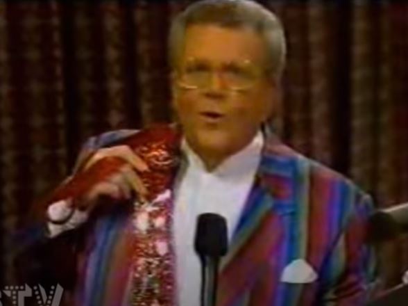 Rod is wearing a red-blue-green striped jacket, white pocket square & white collarless silk shirt