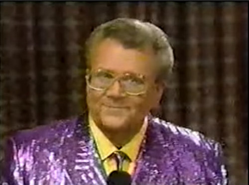 Rod is wearing a shiny purple/purple striped jacket, matching neck tie jacket & yellow shirt