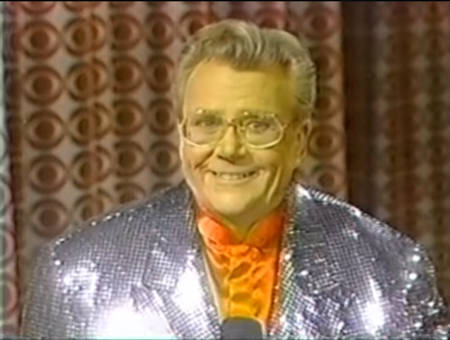 Rod is wearing a silver sequined jacket & red collarless silk shirt