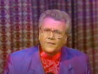 Rod is wearing an iridescent purple jacket & red silk collarless shirt