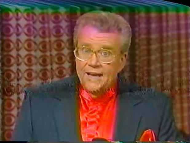 Rod is wearing a dark-green jacket, red collarless silk shirt & matching pocket square