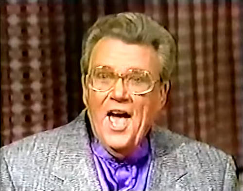 Rod is wearing a grey jacket & purple collarless silk shirt