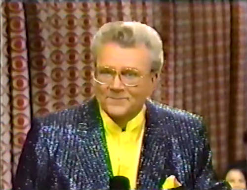 Rod is wearing a black sequined jacket & yellow collarless silk shirt with matching pocketsquare