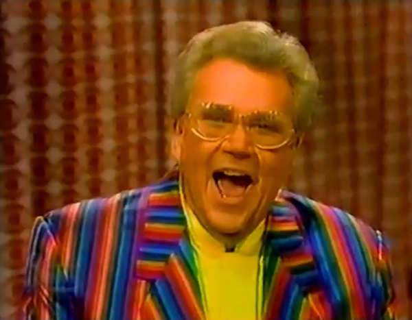 Rod is wearing a rainbow-striped jacket & yellow collarless silk shirt